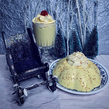 A wintry scene featuring a molded opaque pale yellow gelatin a topped with nutmeg and whipped cream.
