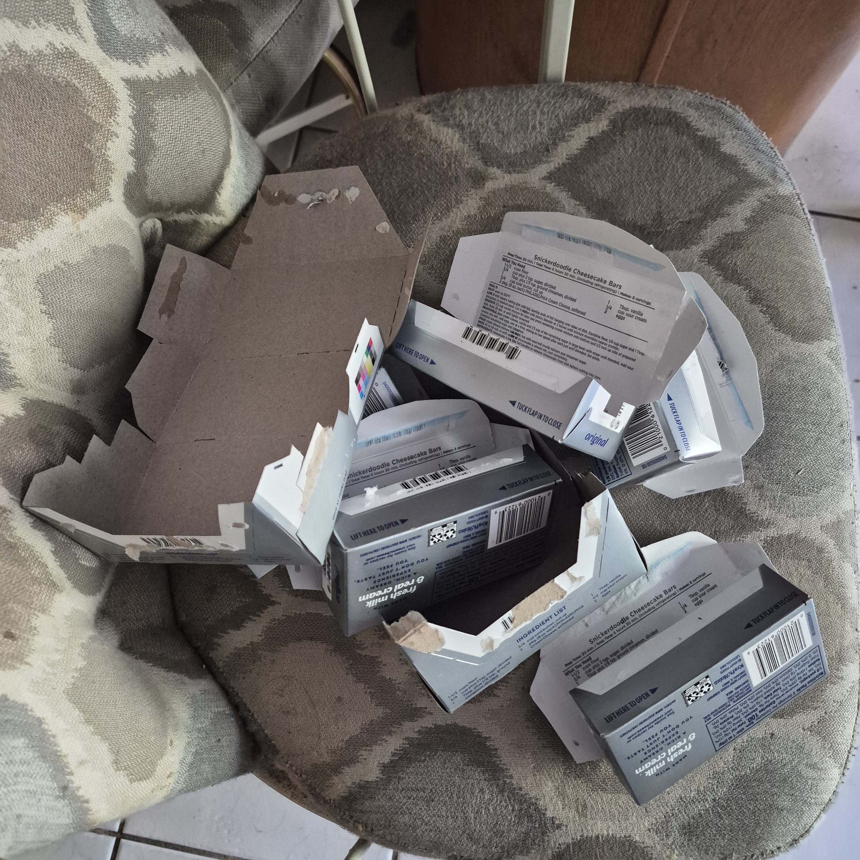 A bunch of empty cream cheese box packaging piled on a chair