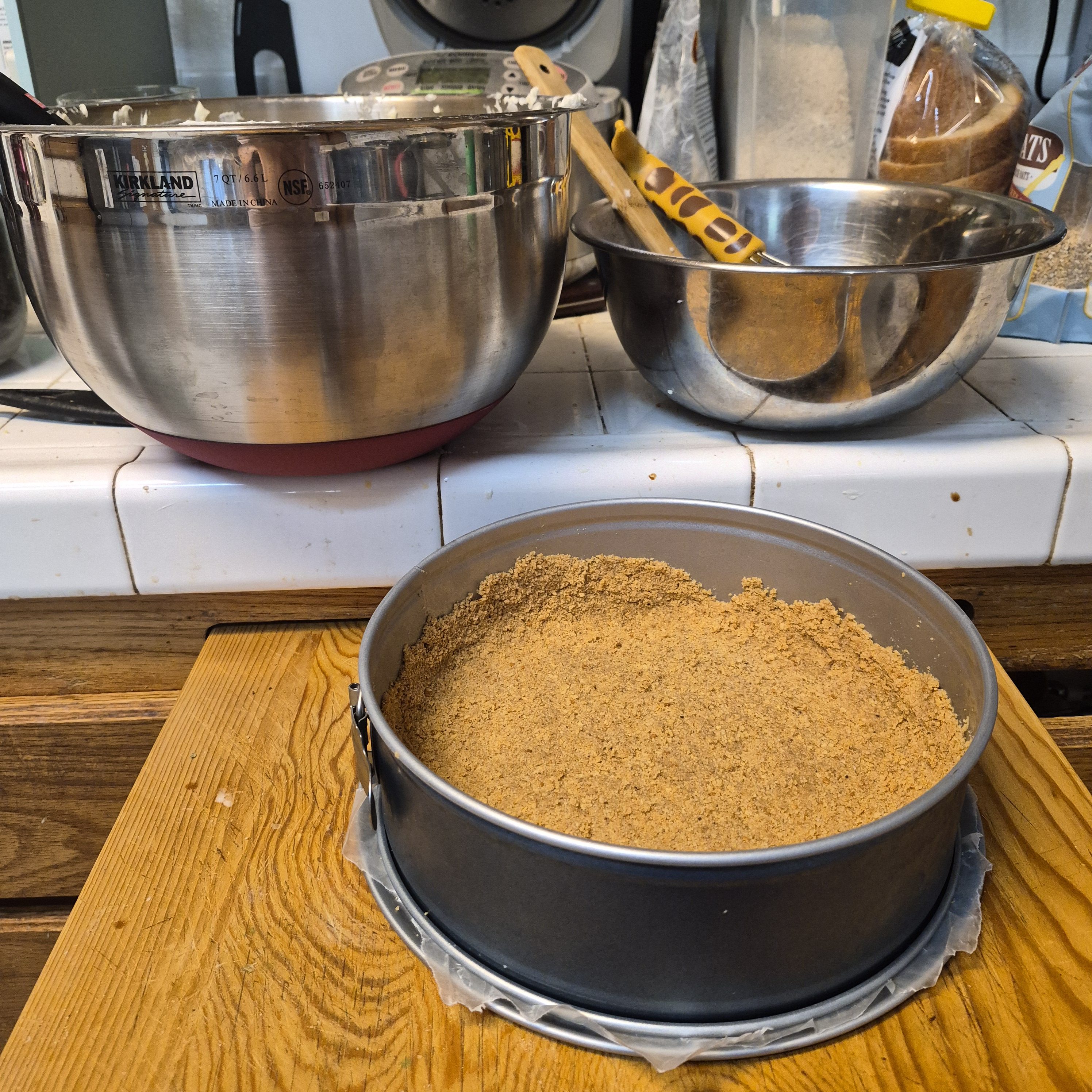 A giant mixing bowl full of cream cheese mixture next to a normal mixing bowl about half its size